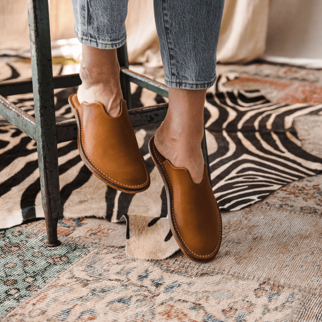 Feet posing with leather slippers on a carpet floor