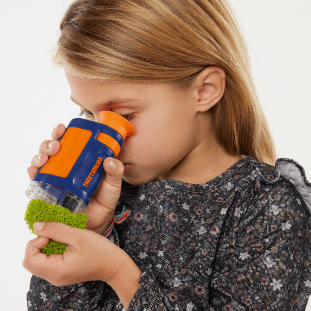 Child looking at a green blob with a TheStemKids magnifying scope