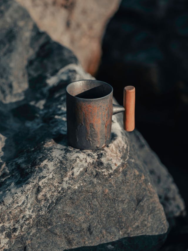 a metal mug placed on a rock