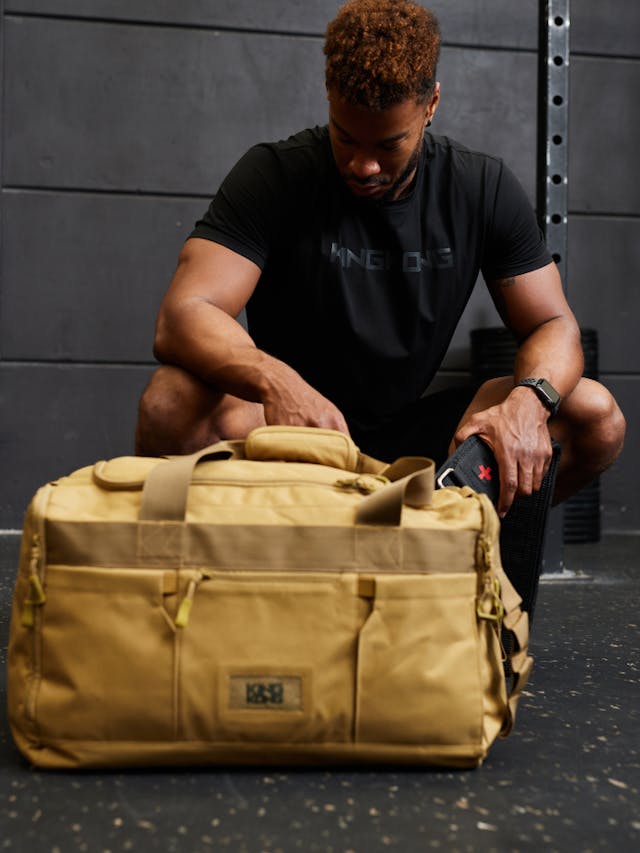 man crouching near a gym bag