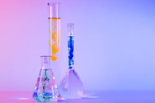 Test tube, conical flask and round-bottom flask with bright-colored chemicals inside