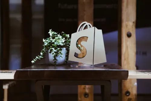 Shopify award featuring the Shopify logo next to a plant on a table