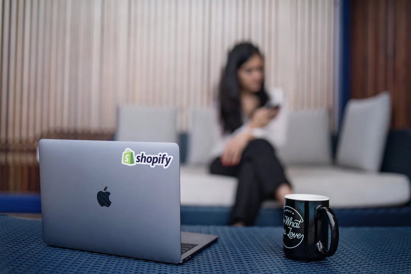 MacBook with Shopify logo and entrepreneur in background